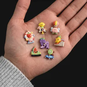 Handheld close-up of colorful cartoon fruit pendants showing exquisite enamel details
