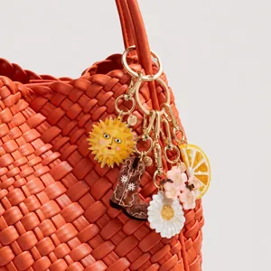 Close-up detail of summer-themed acrylic charms on a vibrant orange woven handbag