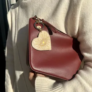 Detailed view of heart-shaped acrylic bag charm with golden sun pattern on red bag
