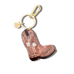 Close-up detail of a marbled acrylic cowboy boot keychain with delicate floral engraving