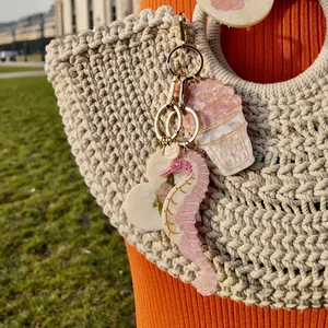 Detailed view of seahorse acrylic bag charm with Solar Eclipse heart tag on a woven beach bag