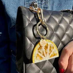 Detail of a textured acrylic lemon slice charm hanging from a black quilted chain bag