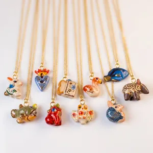 Detailed view of various hand-painted ceramic animal pendant necklaces on gold chains