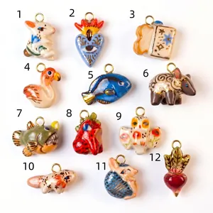 Detailed view of 12 unique hand-painted ceramic animal charms with gold metal loops