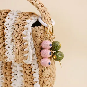 Detaillierte Nahaufnahme von rosa und grünen Obst-Taschenanhängern mit Kristallakzenten.