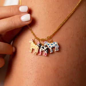 Primo piano di ciondoli cavallo in smalto colorato su una delicata catena in titanio dorato