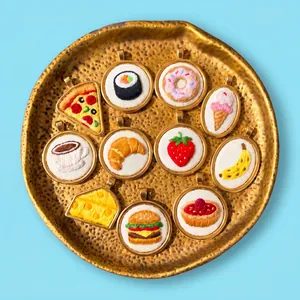 Detailed view of titanium steel embroidered food pendants arranged on a golden plate