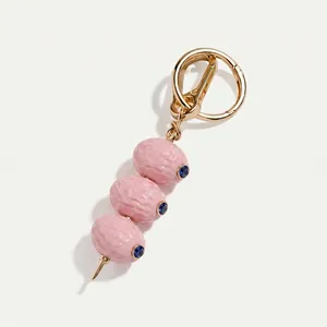 Detailansicht der rosa strukturierten Olivenperlen an einem goldfarbenen Luxus-Schlüsselanhänger