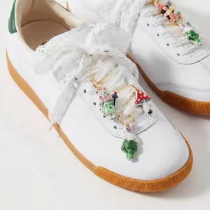 Dettaglio di graziosi ciondoli per scarpe fai-da-te con gatto e fungo su lacci di pizzo