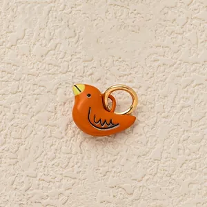 Detailed close-up of a cute orange bird charm with a gold-colored ring for shoes or bags