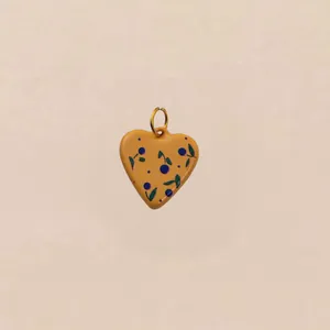 Detailopname van een gele hartvormige bedel met bessenpatroon en gouden ring.