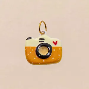 Detailopname van een schattige gele en oranje camera-hanger met hartpatroon.
