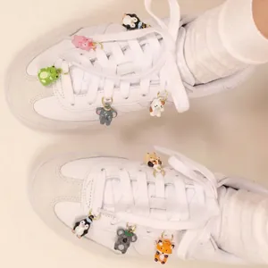 Vue détaillée de jolis charms de chaussures animaux de dessin animé sur baskets blanches