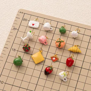 Gedetailleerd overzicht van diverse mini bedeltjes van eten en fruit voor DIY sieraden op mat