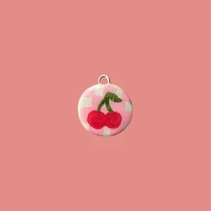 Primer plano del colgante de cereza pintado a mano con fondo de cuadros rosa para joyas