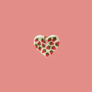 Detalle de un colgante en forma de corazón hecho a mano con motivo de fresa roja