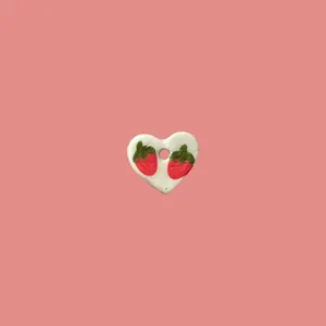Primer plano de un colgante artesanal de cerámica en forma de corazón con fresas