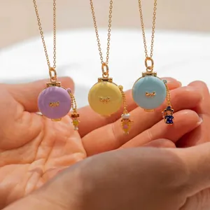 Vista detallada de tres collares relicario de esmalte con dijes de personajes.