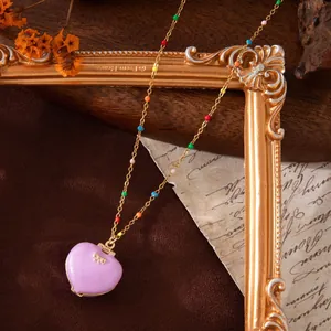 Detailed macro view of a lavender heart locket necklace with colorful beaded chain.