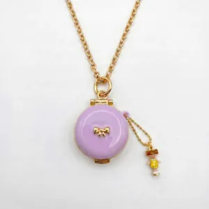 Detalle del collar de medallón de esmalte lavanda con lazo dorado y amuleto de niña