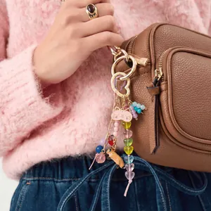 Detailed view of a colorful DIY bag charm with a pink cat and heart beads on a brown bag.