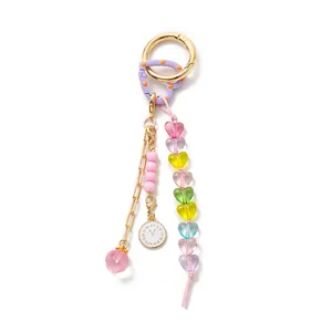 Detailed macro view of a colorful DIY bag charm with heart-shaped beads and clock pendant.