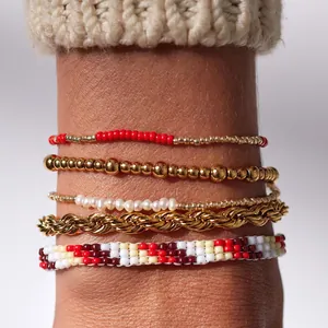 Vue détaillée de bracelets superposés avec perles dorées et perles rouges sur le poignet