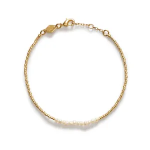 Détail haute résolution d'un bracelet minimaliste en perles dorées avec petites perles