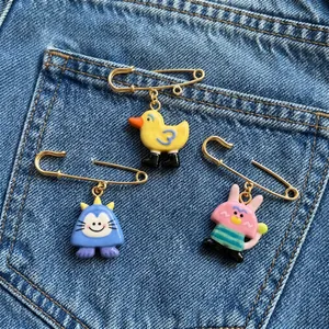 Close-up of three colorful cartoon animal pins attached to blue denim fabric