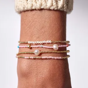 Gros plan de bracelets perlés faits main avec perles naturelles et billes dorées au poignet