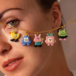 Detailed view of multiple cute cartoon animal pendant charms on a golden link chain necklace