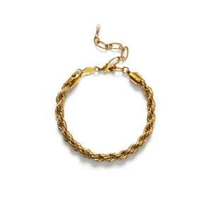 Détail d'un bracelet en chaîne torsadée dorée minimaliste avec une petite perle blanche.