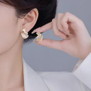 Gros plan de boucles d'oreilles dorées en forme d'éventail avec cristaux sur modèle