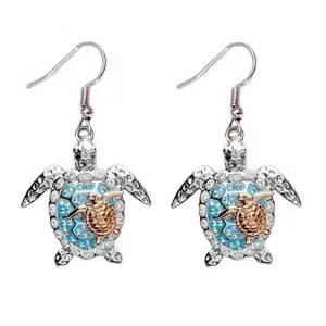 Dettaglio orecchini a tartaruga argentati con strass blu e accento in oro rosa