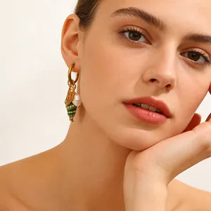 Macro detail of luxury ocean shell earrings with pearl and gold leaf charms on model