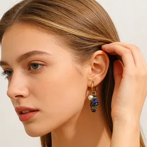 Detailed close-up of a conch shell earring with pearl and blue stone on a female model