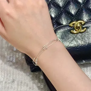 Dettaglio ravvicinato di un bracciale minimalista a più strati in argento con perline.