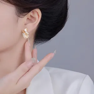 Élégantes boucles d'oreilles éventail dorées avec cristaux de zircon sur un mannequin