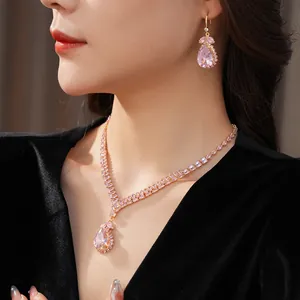 Close-up view of elegant pink teardrop gemstone necklace and earring set on model.