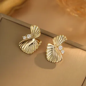 Gros plan d'élégantes boucles d'oreilles éventail torsadées en or avec oxydes de zirconium