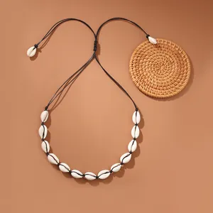 Dettaglio di collana di conchiglie cowrie fatta a mano con corda nera per vacanze