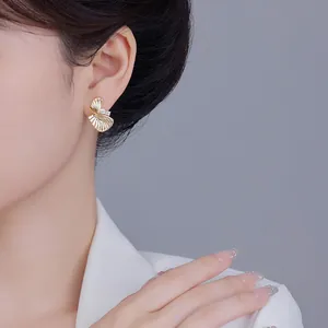 Boucles d'oreilles clous dorées en forme de feuilles torsadées avec éclats cristallins