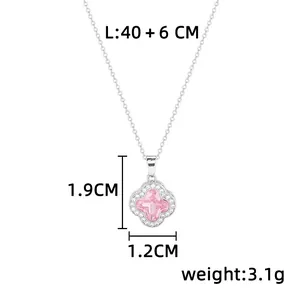 Détail d'un collier trèfle argenté avec cristal rose et pendentif en zircon étincelant.