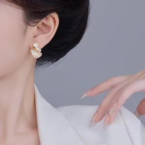 Vue détaillée d'élégantes boucles d'oreilles éventail dorées avec cristaux sur l'oreille