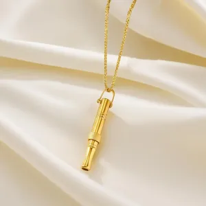 Macro shot showing the intricate details of a golden whistle pendant on satin background.