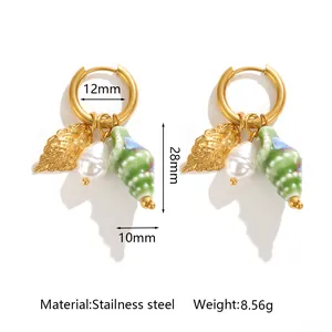 Macro view of stainless steel conch shell earrings with pearl and leaf charms