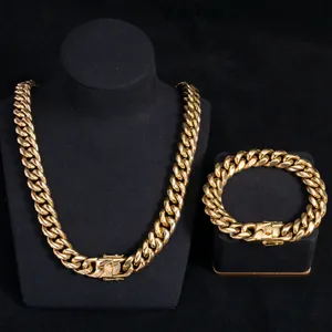 Close-up of a chunky gold-toned Cuban link necklace and bracelet set on black stands