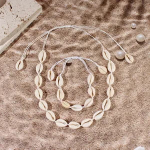 Dettaglio macro di set collana e bracciale fatti a mano con conchiglie su sfondo sabbioso