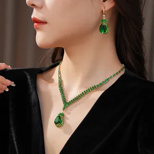 Close-up of elegant luxury jewelry set with teardrop emerald green stones worn by a model
