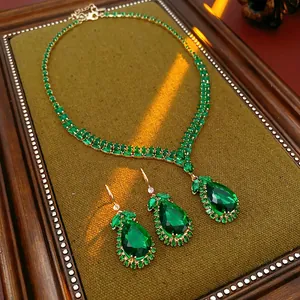 Elegant vintage emerald green teardrop necklace and earrings set on velvet display